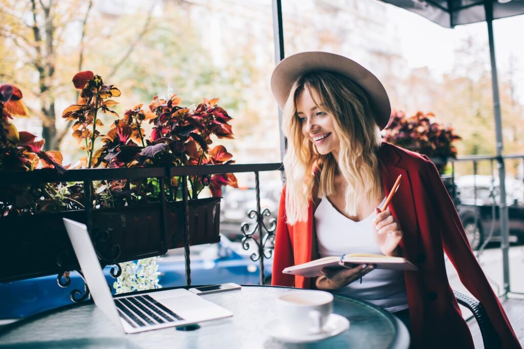 , cheerful hipster girl with textbook for studying watching web webinar
